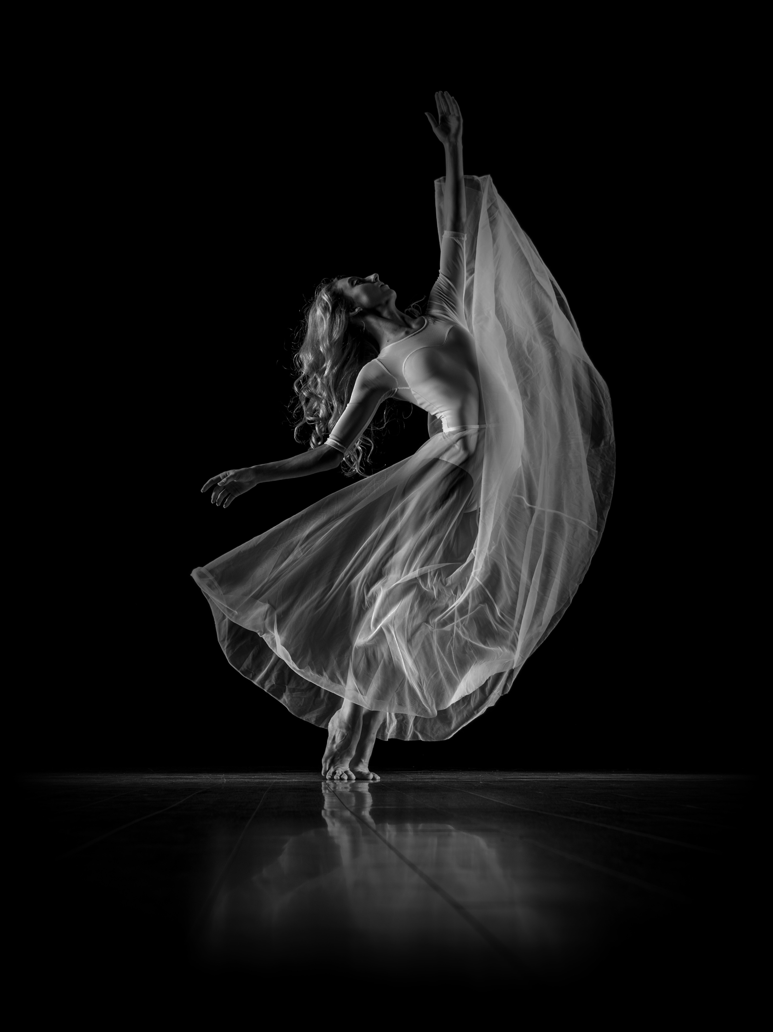 Photograph of dancer in white dress and black background